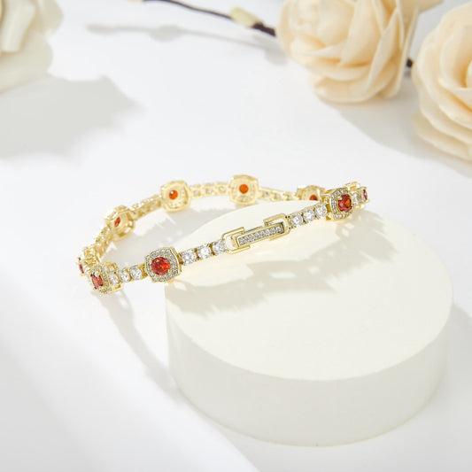 Gold bracelet with red stones on a white surface with flowers