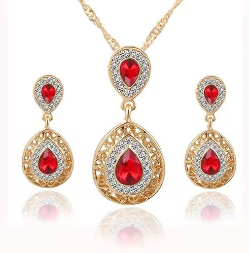 Gold jewelry set with red gemstones on a white background