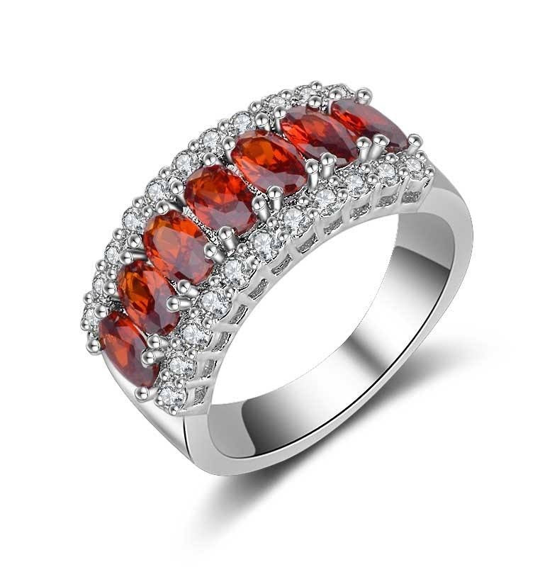 Silver ring with red gemstones on a white background