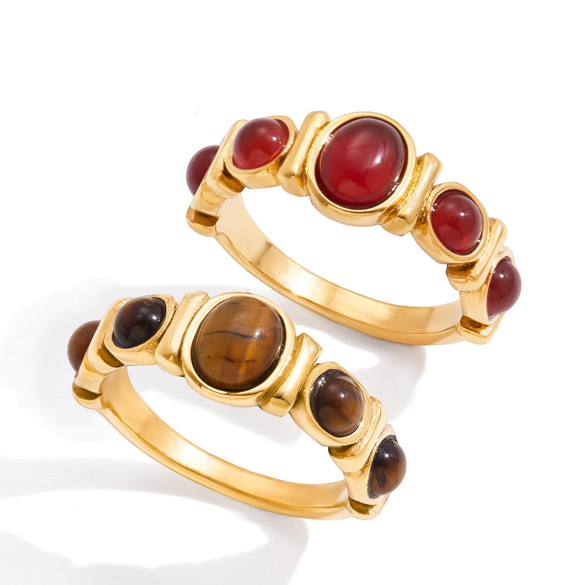 Two gold rings with red and brown gemstones on a white background