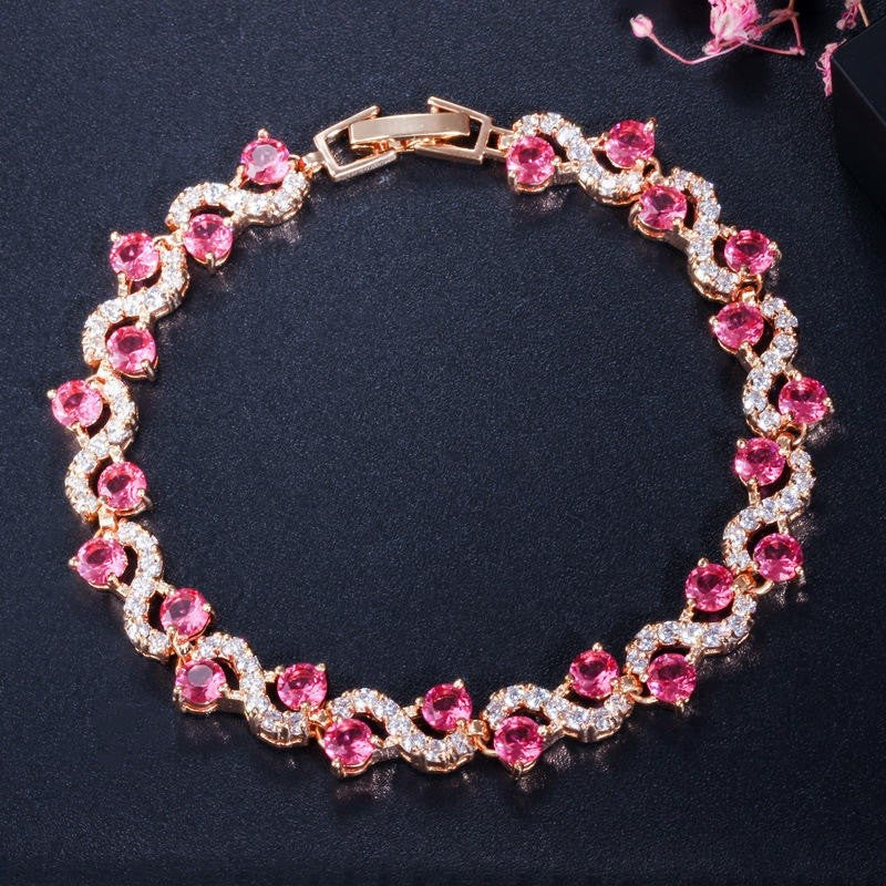 Elegant bracelet with pink gemstones and gold accents on a dark background