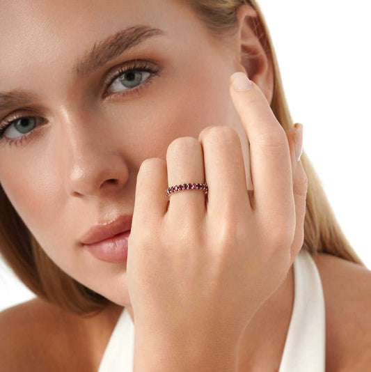 Close-up of a woman wearing a red gemstone ring on a white background