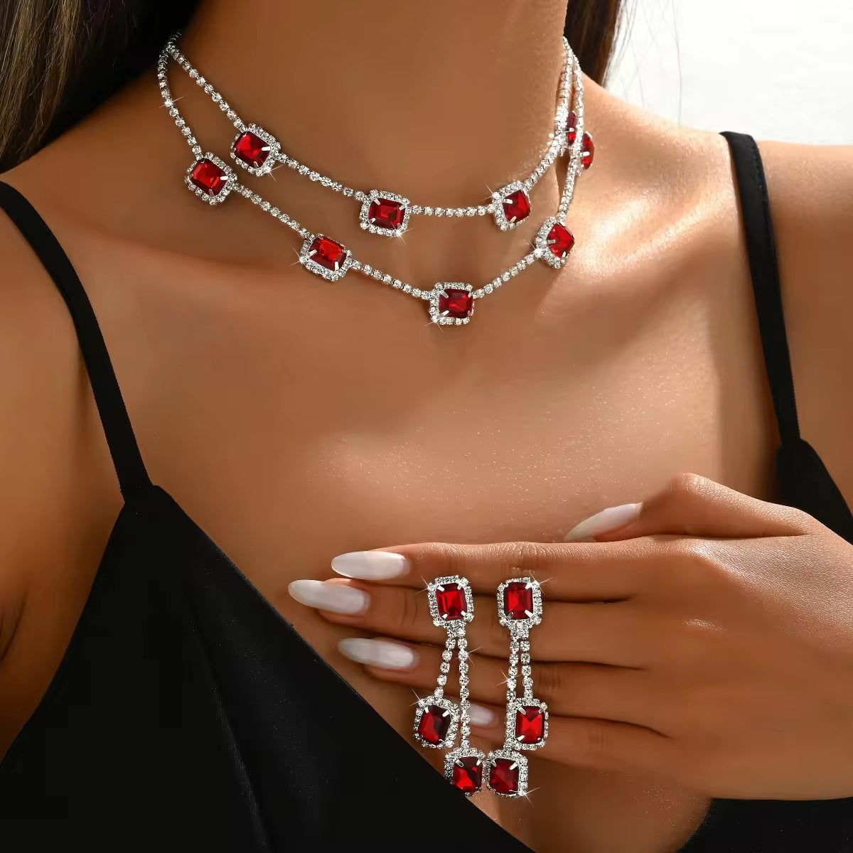 Jewelry set with red gemstones and silver accents on a model wearing a black top.