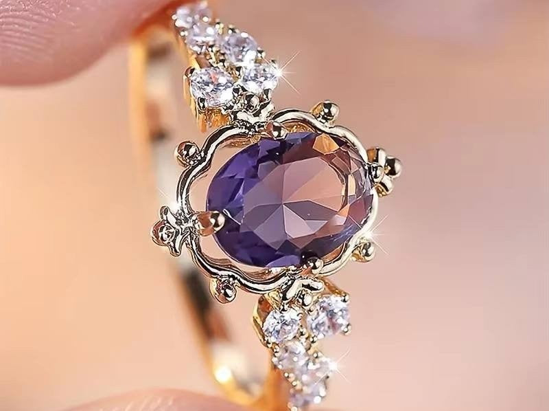 A gold ring featuring a large oval purple gemstone